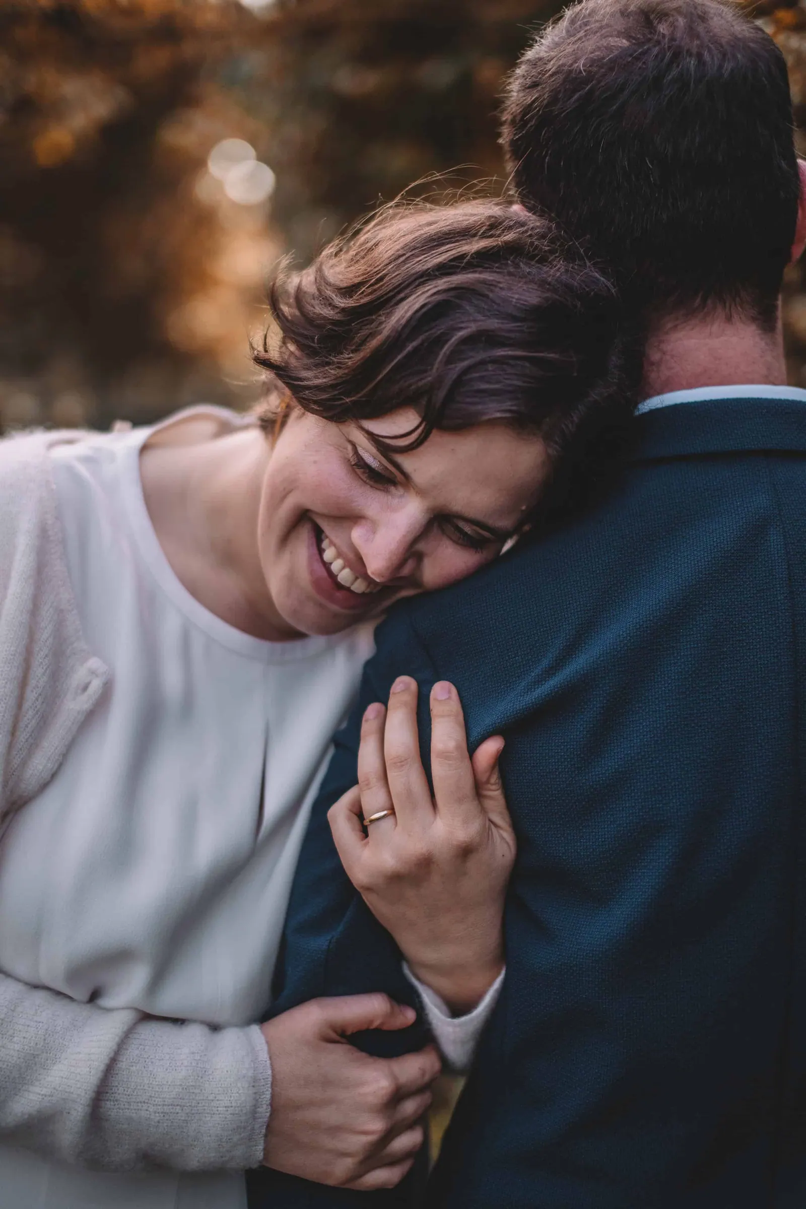 Vrouw legt lachend haar hoofd tegen de schouder van haar partner