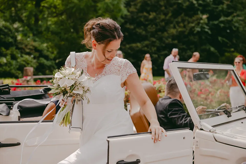 Bruid stapt met haar boeket uit een witte oldtimer