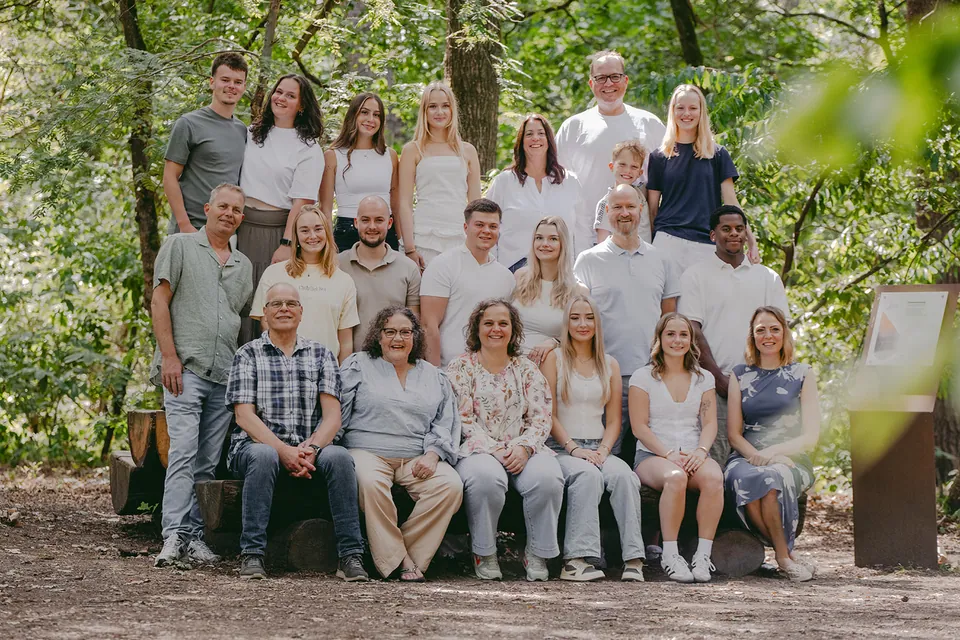 Drie generaties in wit, denim, salie en donkerblauw samen in het bos